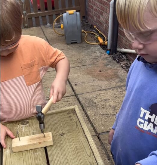 Woodworking at little owls. Two children hammering in nails into pieces of wood.